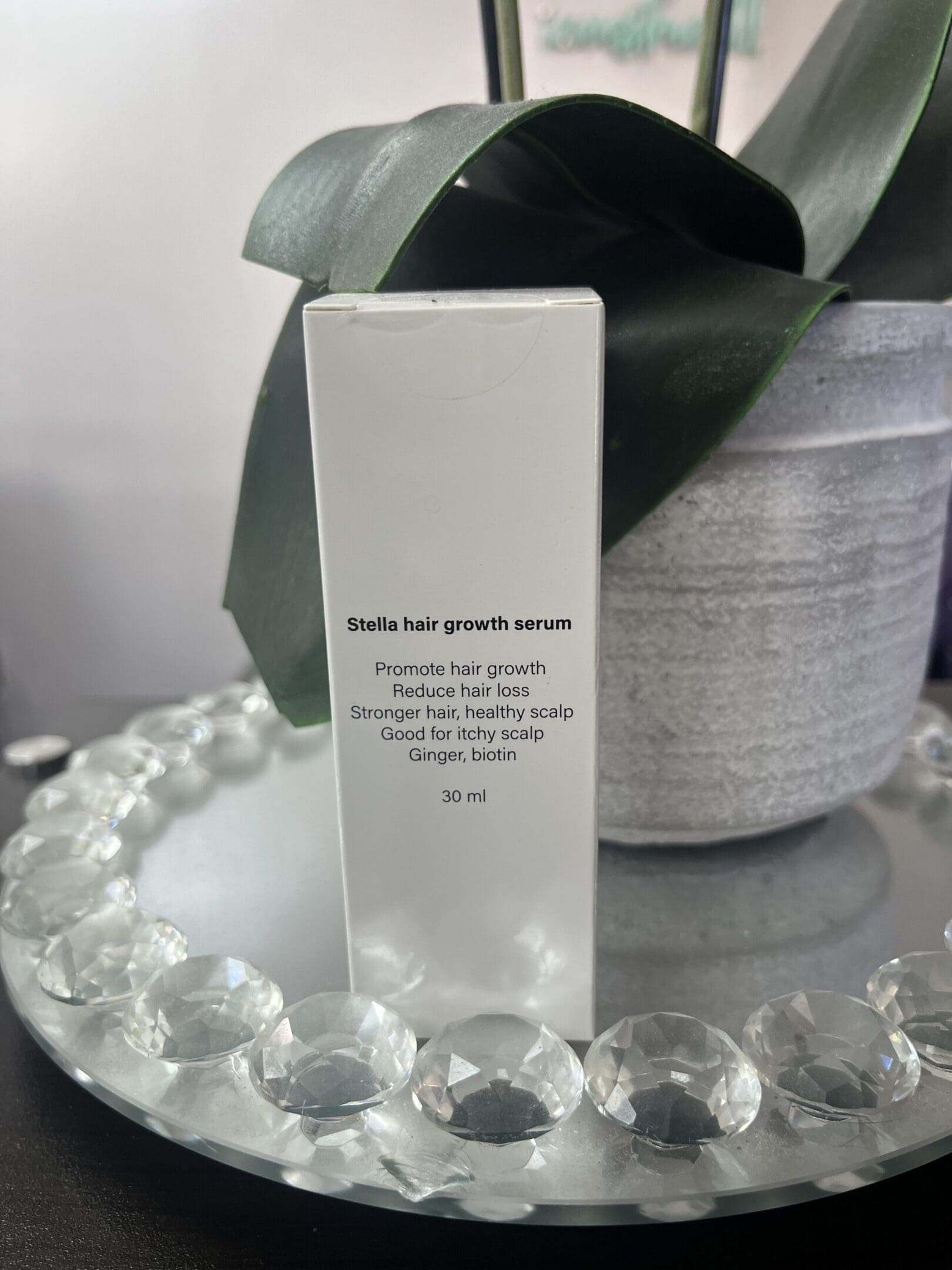 Skincare product box with descriptive text beside a potted plant.